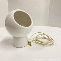 Front and side view of the white ceramic ball lamp showing its crackled finish and power cord with plug and switch.