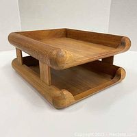 Angled side view of the two-level teak file organizer showing rounded wood corners and open shallow trays for documents.