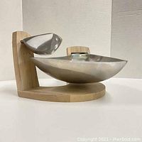 Side view showing cantilevered brushed aluminum chip bowl and smaller dip bowl on curved wooden base holder