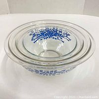 Top-down view of the 3 clear glass Pyrex bowls nested together showing the blue floral and ribbon pattern on each.
