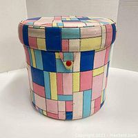 Front view of vintage vinyl JC Penney vanity ottoman with colorful patchwork design.