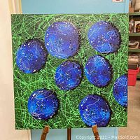 Front view of the Blueberry Madness painting showing large abstract blue berry shapes with green spatter background on the 30x30 inch canvas.