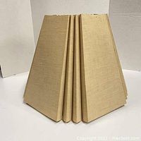 Beige fabric lamp shade photographed from the side showing structured 5-sided polygon design with pleated fabric panels.