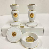 Two white porcelain vintage candle holders featuring gold Athena medallions, standing approx 4 inches tall, with a white lidded trinket box decorated similarly, placed on a white surface.