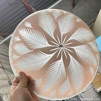Photo showing front of vintage pink glass ceiling light cover with detailed palm leaf design.