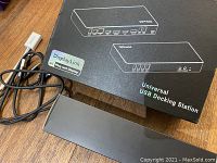 Universal USB Docking Station with box, USB cable, and adapter on wooden surface.