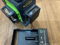 Close-up photo of the front and side of the Valens 3D laser level device with battery charger on wooden surface.