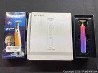 Photo of three items: USB facial trimmer box, Woner hair clipper in white box, colorful T-shaped trimmer outside box