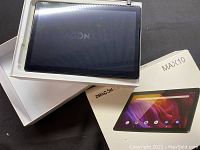 Tablet powered on showing Android startup logo on screen atop open box and packaging.