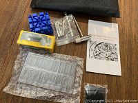 Full view of watch repair kit tools including blue plastic holder, watch band pins, screwdrivers, instruction manual, and accessories.