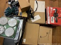 Overview of the lot items including LED string lights with adapter, Bellagon lamp box, and other boxes containing accessories or bulbs.