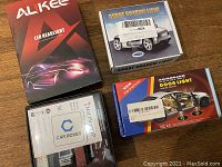 Four boxed car lighting and accessory items placed on wood surface.