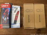 Four tools in their boxes: a UNI-T mini clamp meter box, Preciva pH meter box, and two Towool Wall Stud Finder boxes.