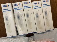 Lot of five unopened PhiCON infrared thermometer boxes displayed upright on a wooden surface.