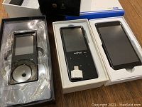 Three digital music players in open boxes showing their screens and accessories, including a charging cable for the Mahdi M310 model.