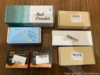 Overview of all 7 boxed items on wood surface including nail grinder box and bark control device boxes