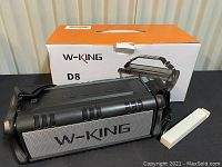 W-KING D8 portable wireless speaker in front of its original box and a small white accessory box.