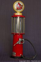 Front view of red vintage SUPERTEST gas pump liquor dispenser with yellow lighted sign on top, clear reservoir, and attached hose and nozzle.