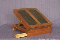 The desk folded with the angled top showing two black panels and a sliding drawer extended.