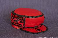 Vintage red leather cap with black braided leather trim and patterned side panels shown front and side on blue background.