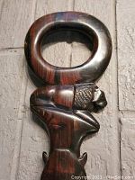 Close-up of the carved lion's head and oval handle of the walking cane, showing detailed carving and wood grain.