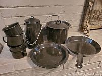 Full set including coffee pot with lid and percolator, cooking pot with lid, frying pan, 4 cups stacked, and 4 plates stacked.