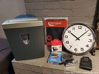 Full shot of the office lot items including shredder, clock, ink cartridges, electronic translator, cell phone holder and tablet holder