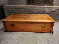 Front view of oak chest showing recessed panel lid and brass pulls