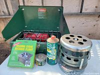 Overview of the Coleman stove with windshields open, Quick-Lite heater, fuel canisters and folding stove box