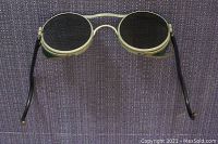 Front view of vintage welding goggles showing round tinted lenses, metal frame with riveted side shields, and black curved temples.