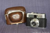 Voightlander VITO CLR camera beside brown leather carrying case showing the front and exterior condition of both items.