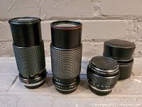 Three vintage camera lenses displayed together, showing overall size and style.