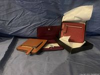 Two new RFID blocking wallets; one tan with a zipper pocket, one burgundy with snap closure.