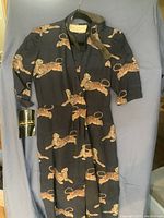 Black long dress with tiger print on fabric hanging on hanger against a blue background showing full dress front.