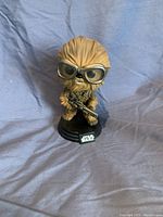 Clear front image of Chewbacca Funko Pop figure showing goggles, detailed fur texture, weapon, and Star Wars labeled base.