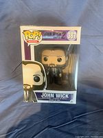 Front view of John Wick Funko Pop vinyl figure in original box with visible figure and labeled as number 387 from John Wick 2.