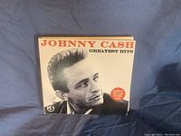 Front view of the tri-fold CD cover featuring Johnny Cash portrait with title Greatest Hits.