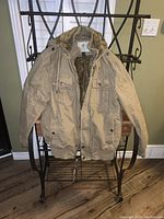 Front view of beige Wenven men's winter jacket hanging on metal rack. Shows front zipper, button closures, multiple pockets and faux fur hood lining.