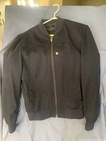 Front view of navy blue men's Zara bomber jacket laid flat on a surface, displaying full zipper and two side pockets.