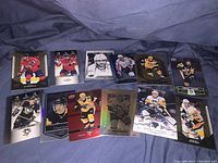 Photo showing 13 hockey cards laid out on a blue fabric background. Cards include multiple of Alex Ovechkin and Sidney Crosby hockey cards from different sets, some with foil or holographic designs.