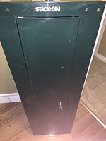 Front view of closed green Stack-On safe with key lock visible on door.
