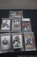 Seven hockey cards displayed on black background; one graded CBCS, six encased in transparent plastic plaques with screws.