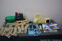 Wide view of entire lot layout including train engine, multiple tracks, playset pieces, and books