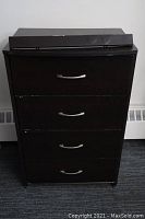 Full front view of the four drawer dark brown dresser showing metal handles and detached top piece of wood.