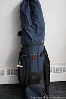 Full view of the blue and black golf bag standing upright with shoulder strap and stand mechanism visible.