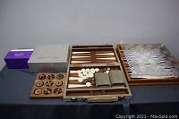 Wide view of the lot showing glass chess board, wooden tic tac toe, and backgammon board on a table.