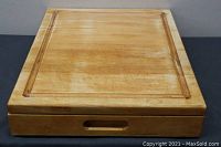 Front view of wooden cutting board showing the juice groove and drawer handle.