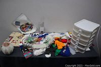 Wide view of lot consisting of various sewing tools and materials on a table, white multi-drawer organizer on the right side.
