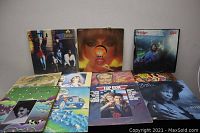 Photo showing 10 vinyl record album covers laid out on a floor, revealing a variety of album arts and artists.