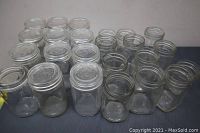 Set of 22 clear glass jars of varying sizes and shapes arranged on a surface.